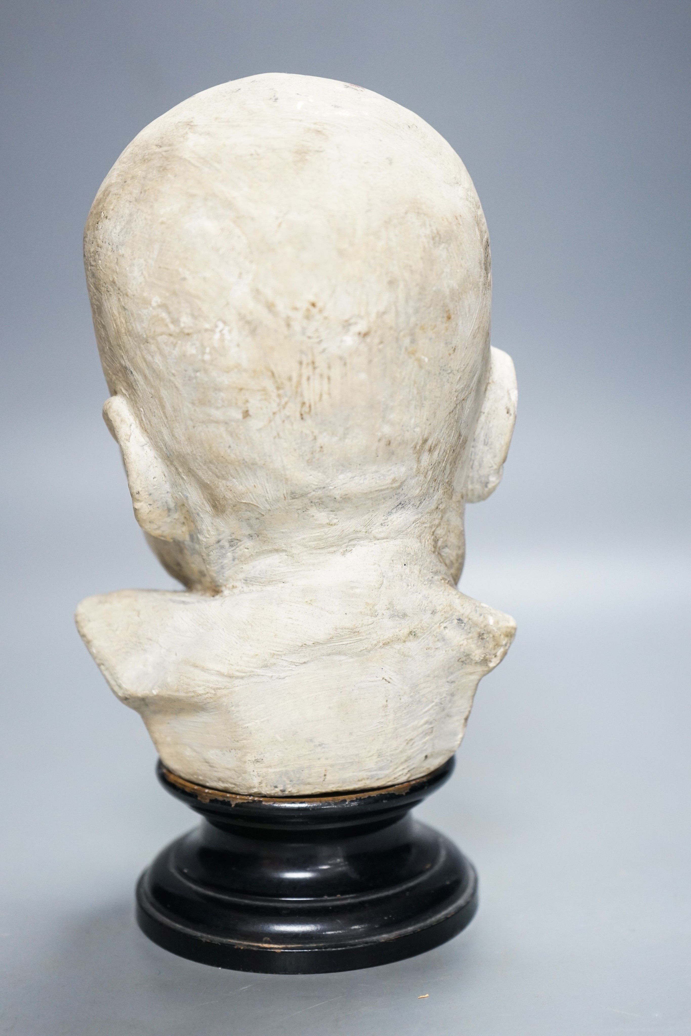 A 19th century memento mori plaster bust of an infant, on ebonised socle 22cm